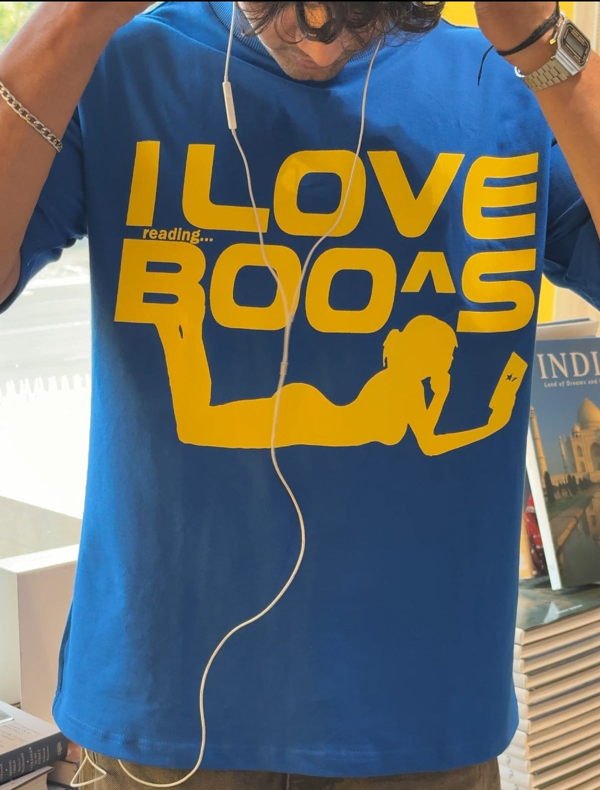 Person wearing a blue t-shirt with yellow text and graphics in an indoor setting.