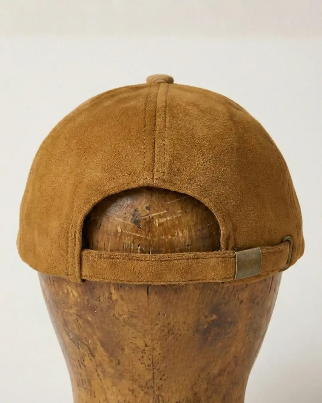 Back view of brown suede baseball cap with metal strap, teeside accessory